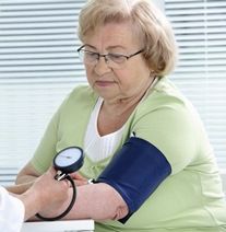 Señora mayor en la consulta del médico tomándose la tensión.